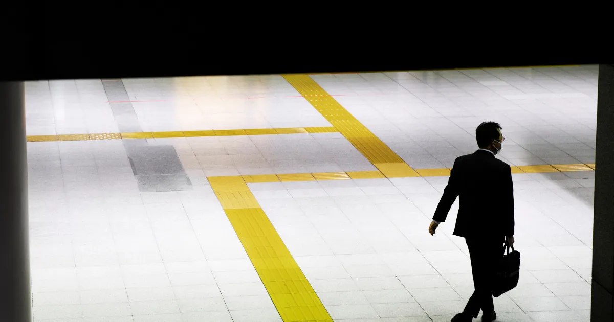 夜の街を一人歩く男性。転職活動の孤独を感じ少し寂し気に歩いている