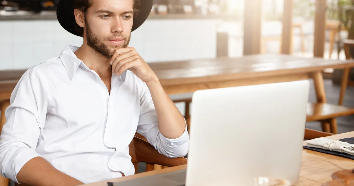 デスクに座りパソコンの画面を眺めながら考えを巡らせる男性。webライターとして活動し、今まさに記事を執筆している