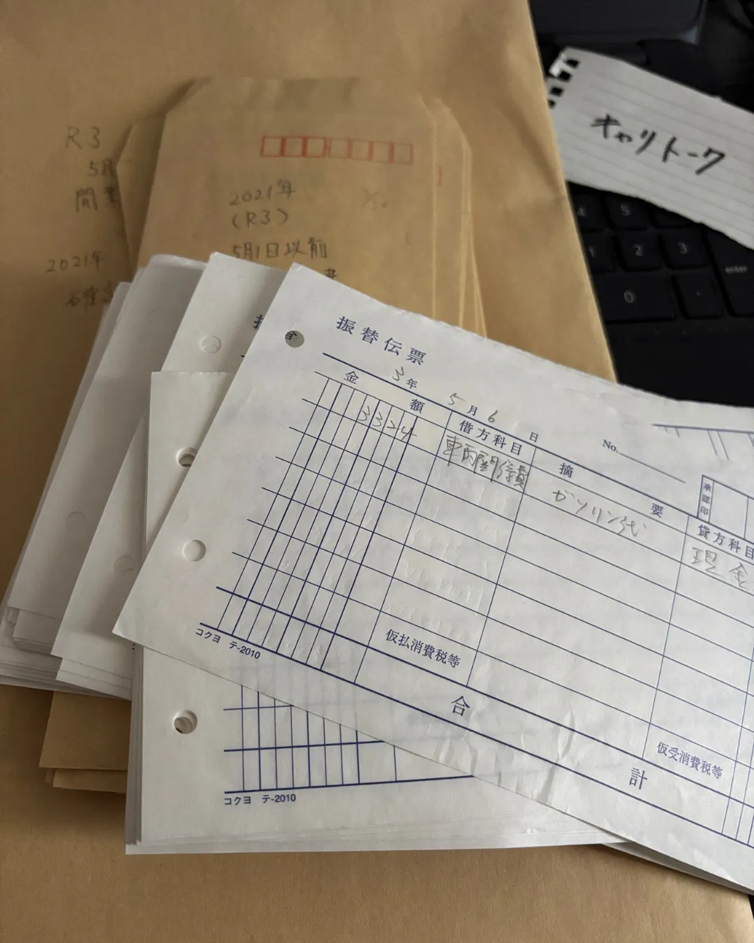 2021年(令和3年)の振替伝票と経費管理用の封筒。個人事業主ドライバー時代のガソリン代などの記帳と、ブログ「キャリトーク」の直筆メモ。