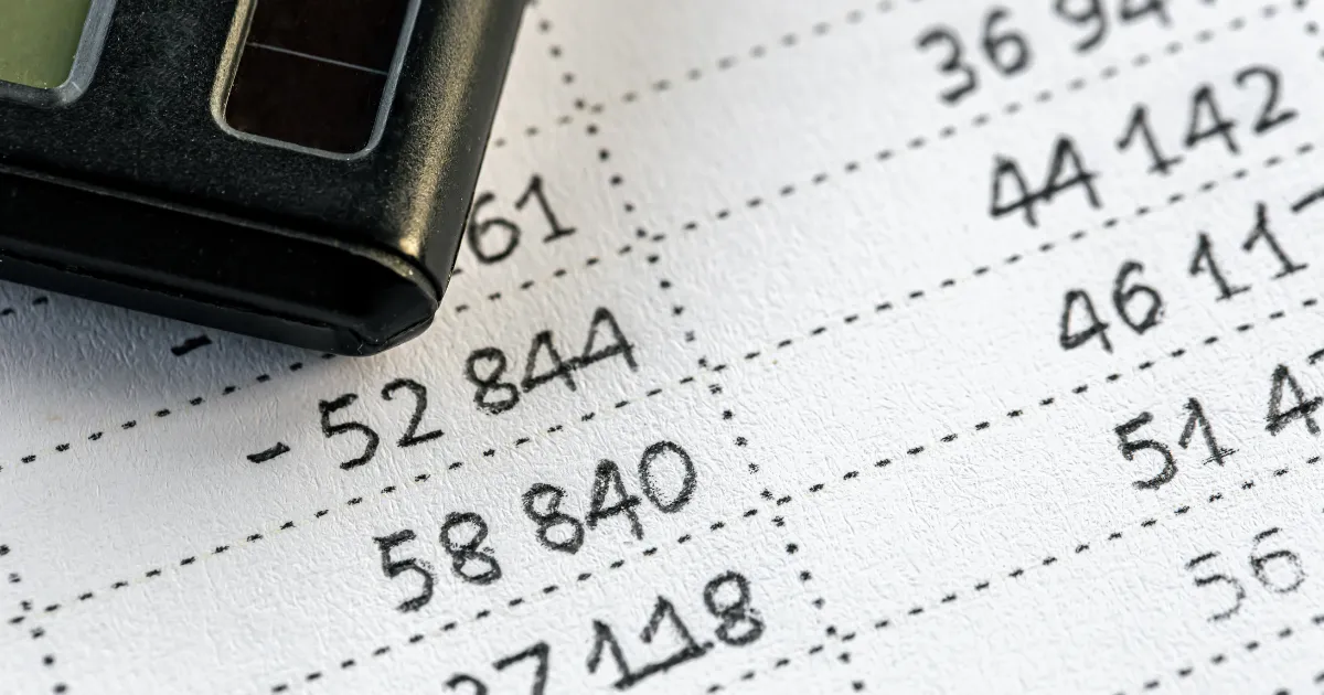 売上と経費が書かれたノートと電卓の画像