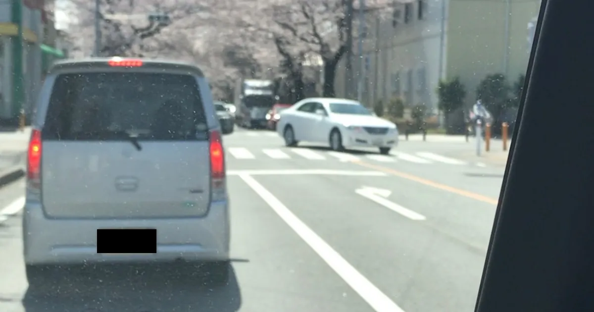 転職後に自信を失い、昼休みに逃げ込んだ軽自動車の車内から見た景色。外は桜が咲いているが、心は暗く沈んでいる。