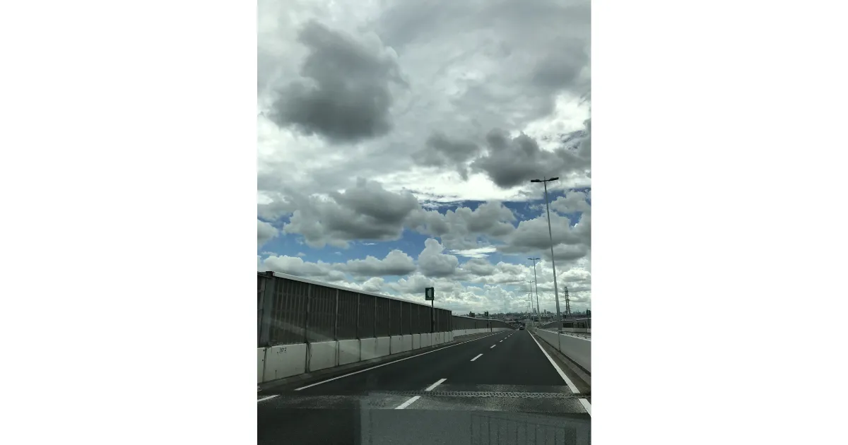 トラックの運転席から見上げる、雲の多い広い空と高速道路の景色